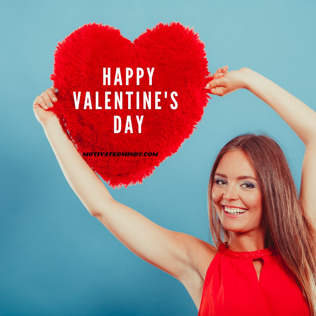 A girl wearing red dress showing a red heart furry pillow.